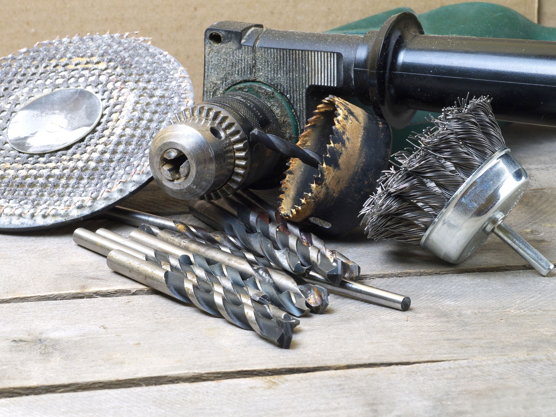drill machine and attachments - wire brush, hole saw, grinding circle and assorted bits on wooden table