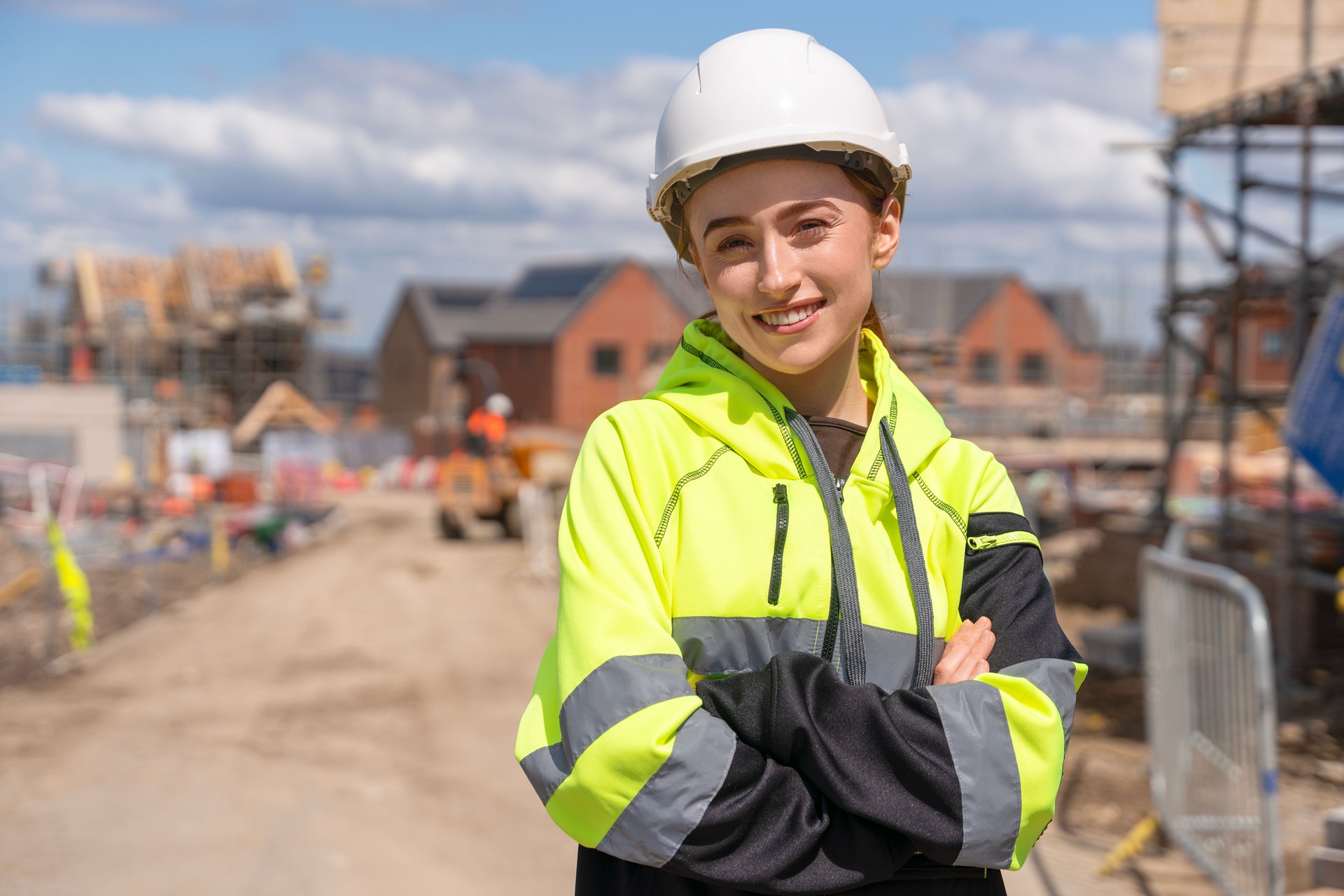 Portrait of young woman construction worker in safety gear standing confidently on building site
